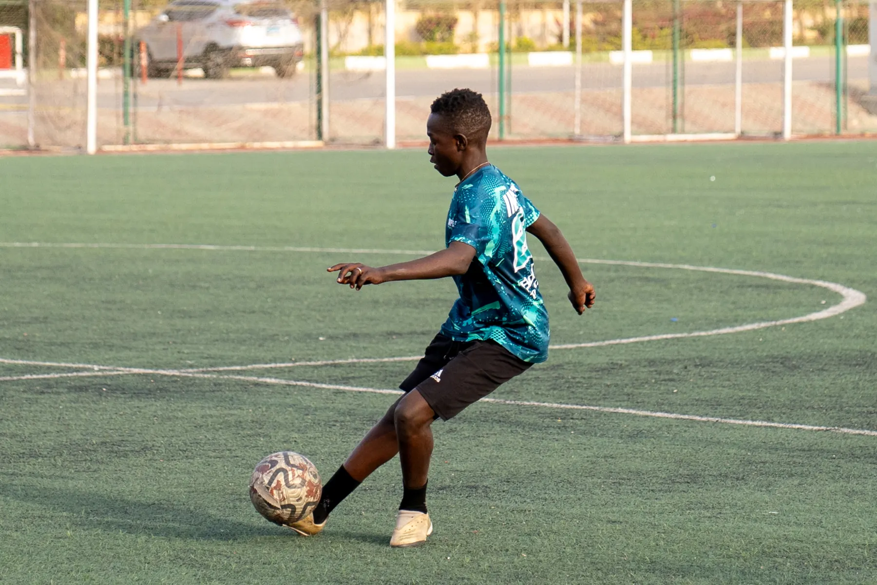An academy player strikes the ball on an artificial-turf pitch