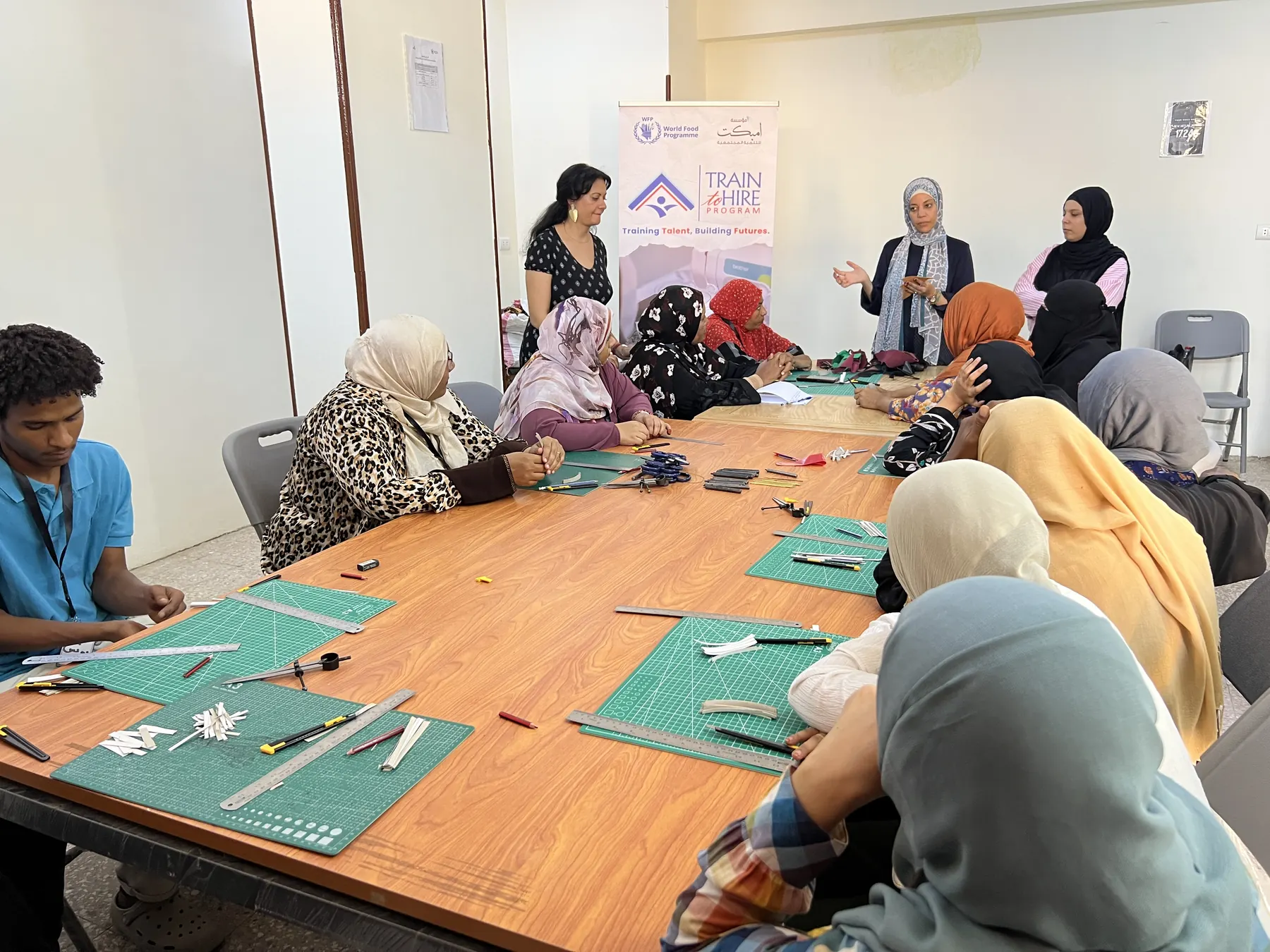 Trainees work on leather pieces around a large table in Aswan